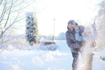 Winter walk on the street on a sunny frosty day. Family with children play snowballs in the park....
