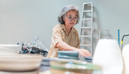 Senior Female Business Owner Inspecting Ceramics