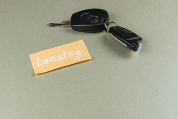 Keys and leasing note on a grey surface for vehicle rental options