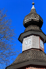 Bell tower with old mechanical clock with Roman numerals and only an hour hand against blue sky. Church of St Lawrence, Pernio, Finland.