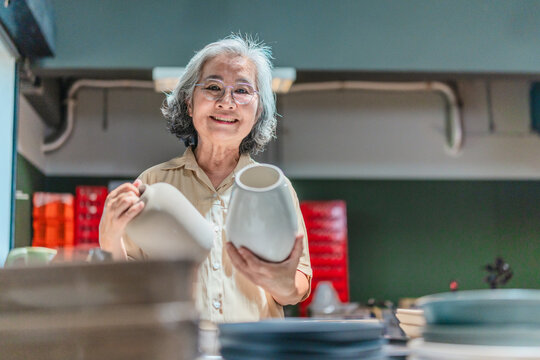Senior Female Business Owner Inspecting Ceramics
