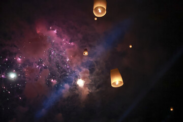 Spiritual festival celebration at night with floating sky lantern and colorful firework. beautiful light in dark sky inspires magical and hopeful feeling