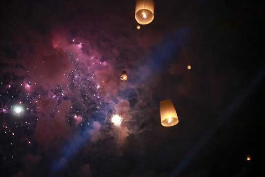 Spiritual festival celebration at night with floating sky lantern and colorful firework. beautiful light in dark sky inspires magical and hopeful feeling