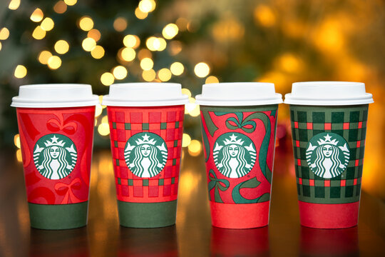 A row of Starbucks beverages in the new 2025 designed festive holiday cups, in Dallas, Texas, on November 9, 2025. Christmas lights background.