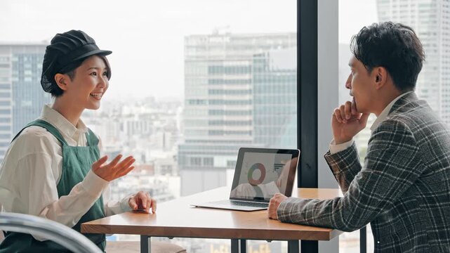 店内で面談する飲食店店員とビジネスパーソン