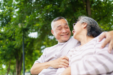 Happy senior Asian couple relaxing together on bench. Retirement couple lifestyles.