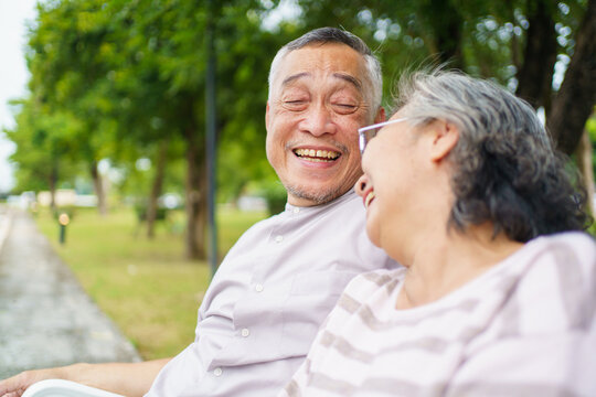 Happy senior Asian couple relaxing together on bench. Retirement couple lifestyles. - Powered by Adobe