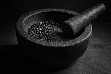 Mortar and Pestle: A detailed close-up of a rustic mortar and pestle, showcasing texture of the stone, alongside a collection of peppercorns.