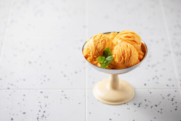 Natural fruit orange ice cream or sorbet in ceramic bowl