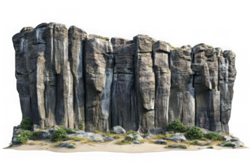 Tall grey columnar rock formations with green vegetation on sandy ground cliff mountain