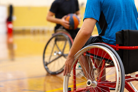 two anonymous men in wheelchairs on a basketball court