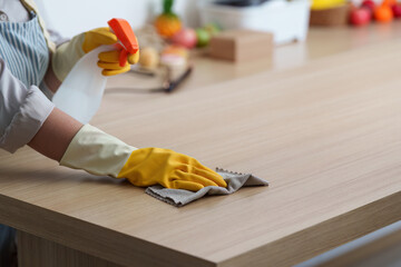 Home Cleaning. Woman wiping kitchen table with spray and cloth.