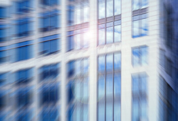 An architectural urban high-rise with reflective windows, captured with a dynamic radial blur effect and a sun flare.