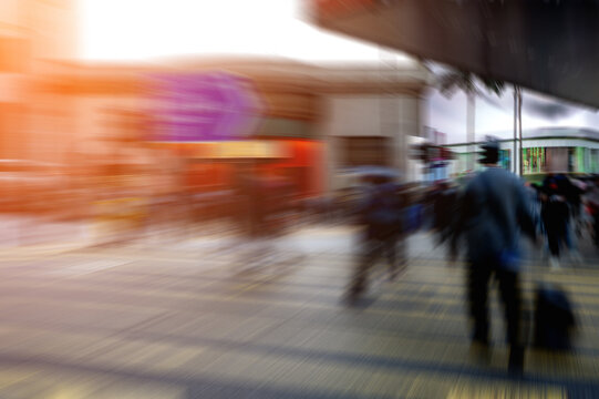 Dynamic, blurred urban scene with architectural elements, capturing city life's fast pace. A radial blur effect and bright sun flare.