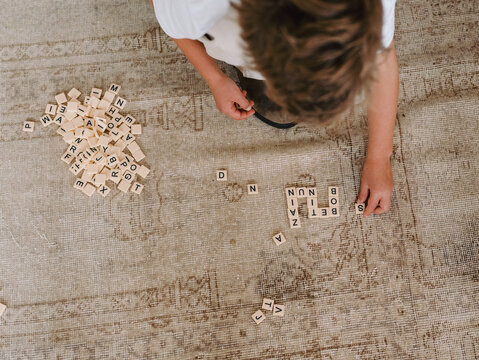 Young boy playing crosswords on carpeted floor