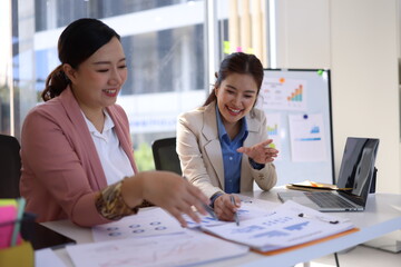 Two businesswoman working with business financial graph data and marketing plan at desk in office, Business concept.