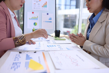 Two businesswoman working with business financial graph data and marketing plan at desk in office, Business concept.