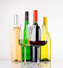 Different wine bottles and glasses on white background
