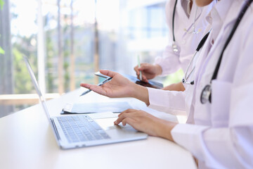 Two medical doctors working on laptop with tablet and a CT scan in clinic office, Body x-ray film,...