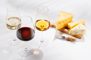 Fototapeta premium Assorted cheeses and wine glasses on white background