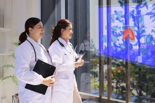 Two professional female doctor working with human anatomy virtual interface icons. Medical technology and Healthcare concept. 