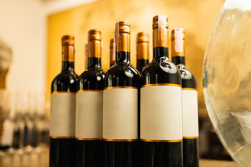 Collection of red wine bottles with blank labels, perfect for mockup. Set against a warm, golden background.