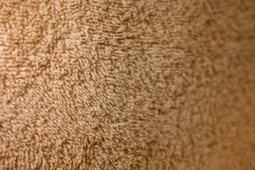 Macro shot of a soft brown terry cloth fabric. The selective focus on the fluffy, absorbent loops creates a warm, textured background with ample copy space for spa or home concepts.