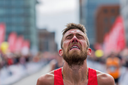 Solo marathon runner reaching finish line with exhausted expression