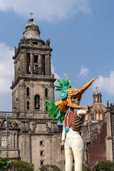 Fototapeta premium A skeleton dressed in a costume with a bird head and a skeleton's face is standing in front of a lar. Mexican Day of the Dead tradition, offerings, food, colors, decorations, and papel picado, La Catr