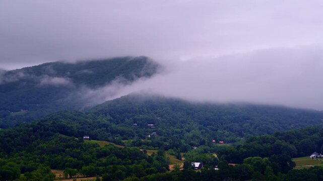 Aerial view from a drone drifting over a serene, foggy mountain valley.