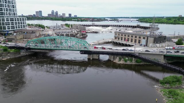 A bridge hydro electric dam and waterfall on an urban river. Tracking aerial shot.