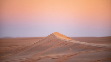 Serene desert landscape at sunset with soft pastel sky and sand dunes