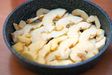 Sliced apple half-rings arranged in a single layer on a pan bottom for apple pie