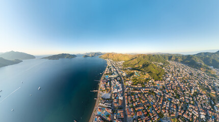Marmaris, Turkey. Panoramic aerial view of coastline with beaches and hotels, city and forested mountains in morning sunlight. Coastal urban landscape. Aerial view.
