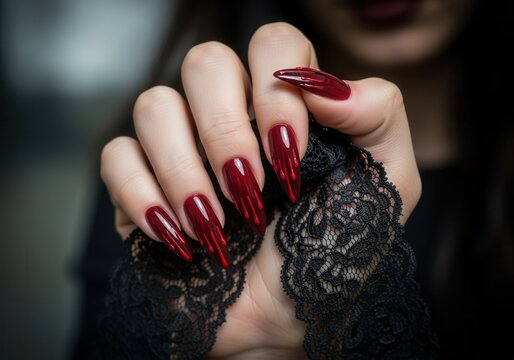A woman's hand with a red Halloween manicure and dripping blood nail art. Close-up of long stiletto nails with a gothic vampire style
