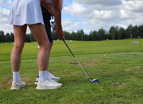 Golf swing practice at a driving range on sunny day with scattered clouds and green grass