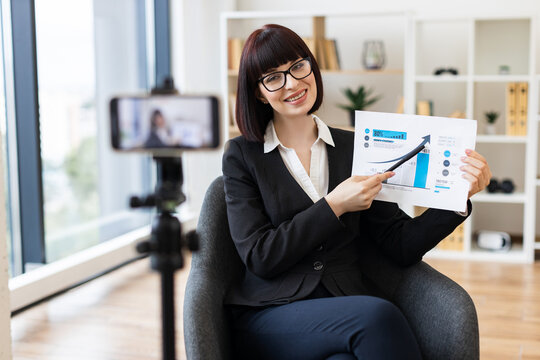 Caucasian woman in thirties presenting business growth report during live video blog recording - Powered by Adobe