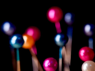 Vibrant orbs on sticks create an abstract scene with a dark background, evoking playful festivity.