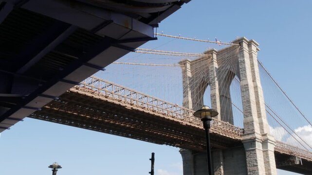 Brooklyn Bridge from Manhattan Downtown, New York City, United States. Bridge to Dumbo from esplanade pier park in NYC USA. American architecture, famous tourist landmark. Waterfront urban promenade.