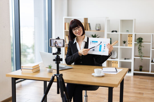 Caucasian woman presenting business data in office, recording blog or video with professional equipment