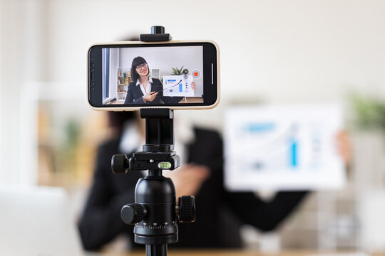 Caucasian young adult woman sitting at table holding presentation while recording blog. Concept of business, communication, and content creation. - Powered by Adobe
