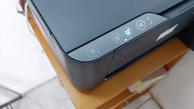 Close-up of Finger Pressing the Power Button off a Black Printer or Scanner