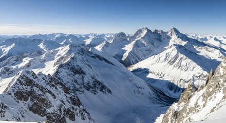 A breathtaking panoramic view of snow-covered mountain peaks under a clear blue sky during daytime, showcasing the majestic beauty of a winter landscape