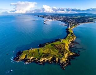 Aerial view of a coastal peninsula with a town, pier, and calm sea on a sunny day