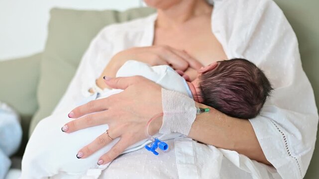 Mother breastfeeding newborn baby in hospital maternity ward