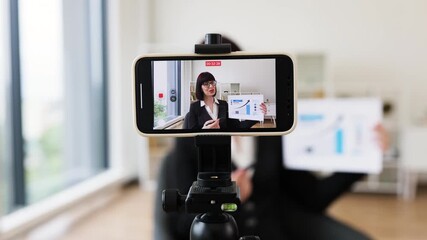 Caucasian woman presenting business charts and growth analysis while being recorded through smartphone setup - Powered by Adobe
