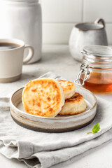 Cottage cheese pancakes or syrniki on ceramic plate on light gray kitchen table. Healthy sweet breakfast