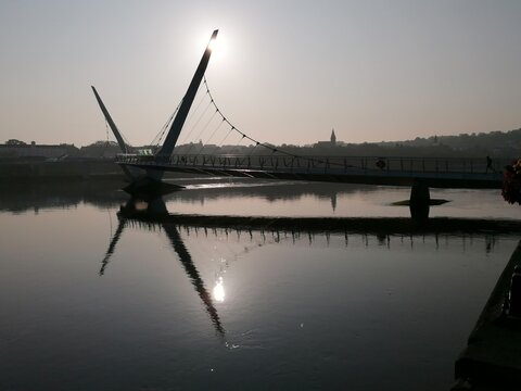 The Peace Bridge in Derry, Northern Ireland, stretches gracefully across the River Foyle. Taken at sunrise, the calm reflections and warm light highlight the bridge&rsquo;s symbolism of peace and connection