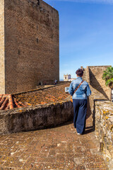 Exploring the Past: Woman Walking the Battlements of Olivenza Castle Wall, Next to the Majestic...