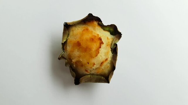Traditional Minang baked bika cake served on a waru leaf, a sweet coconut snack from West Sumatra, Indonesia, isolated on white background. Flat lay